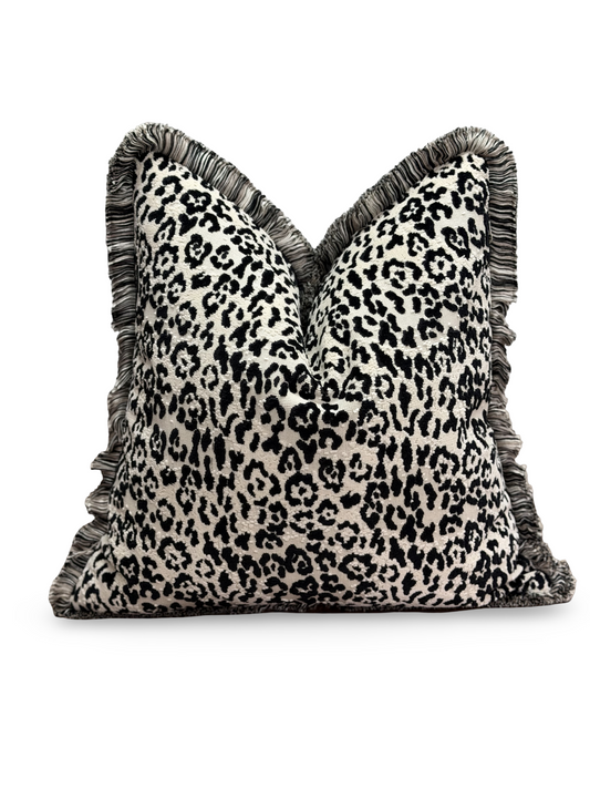 A square throw pillow with a black and off-white leopard print pattern and fringed edges, shown against a plain white background.