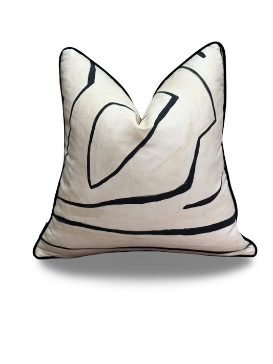 A square throw pillow in cream with black abstract line art and black piped edges, shown on a white background with a soft drop shadow.