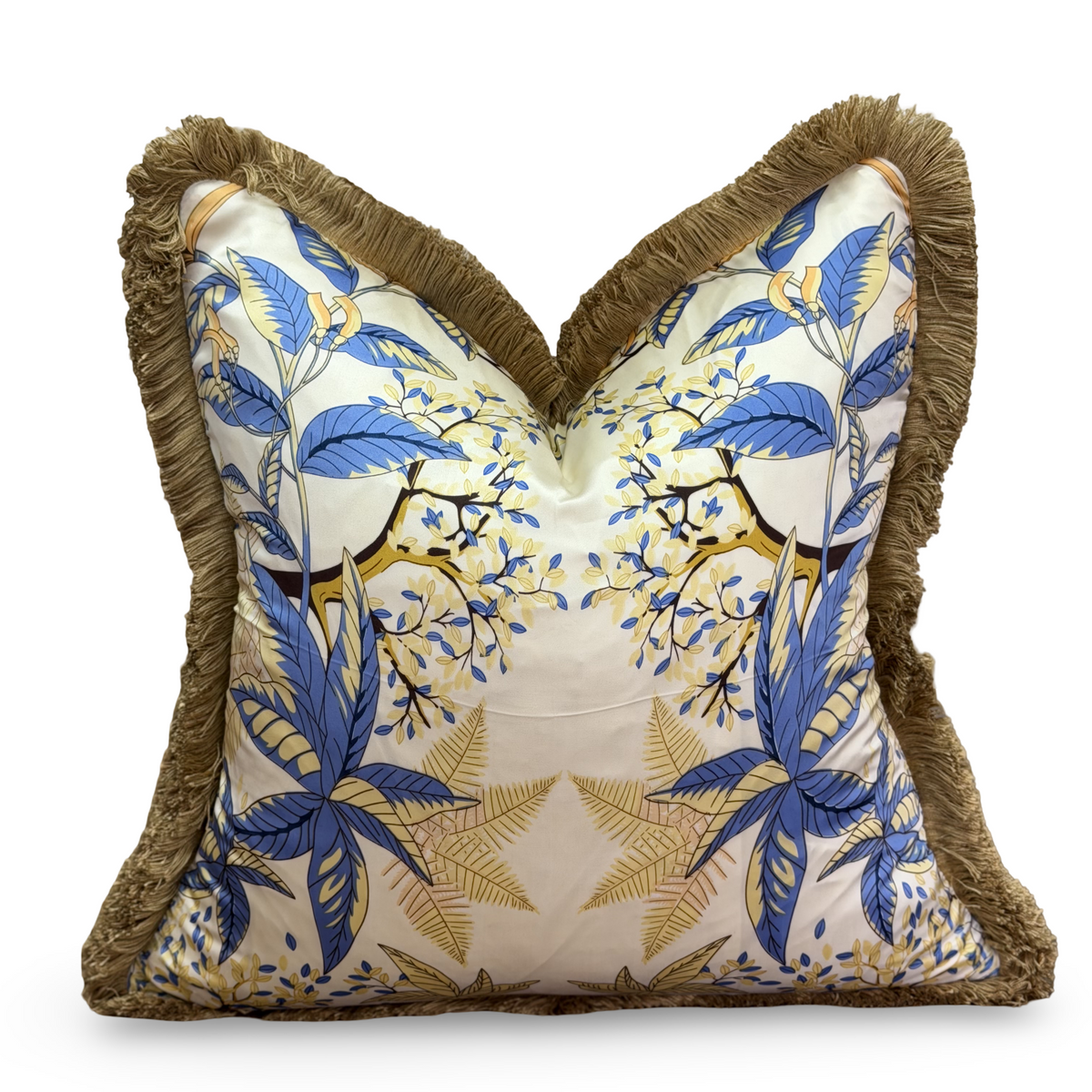A square decorative throw pillow with a heart-shaped pointed top, featuring a blue and gold tropical floral pattern on a cream background, finished with a brown fringed border.