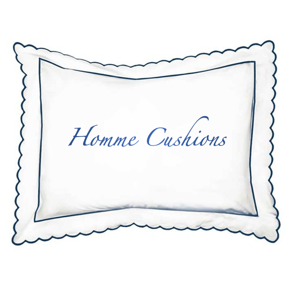 A white rectangular decorative pillow with a scalloped blue border and the words 'Homme Cushions' embroidered in blue script in the center, shown on a plain white background.